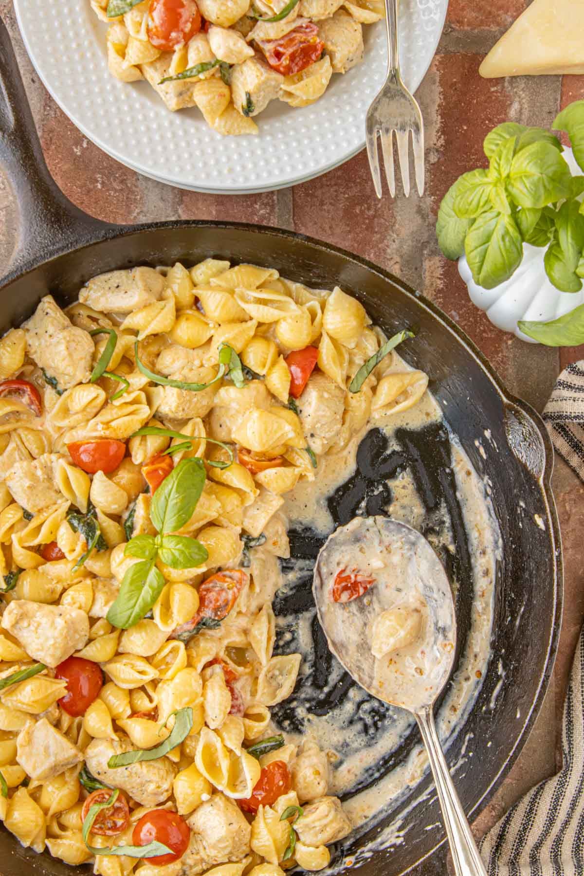 Creamy chicken spinach pasta skillet served in a black skillet with Parmesan cream sauce and fresh basil”