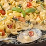 One pot chicken spinach Alfredo pasta served in a black skillet with creamy Parmesan sauce and fresh basil