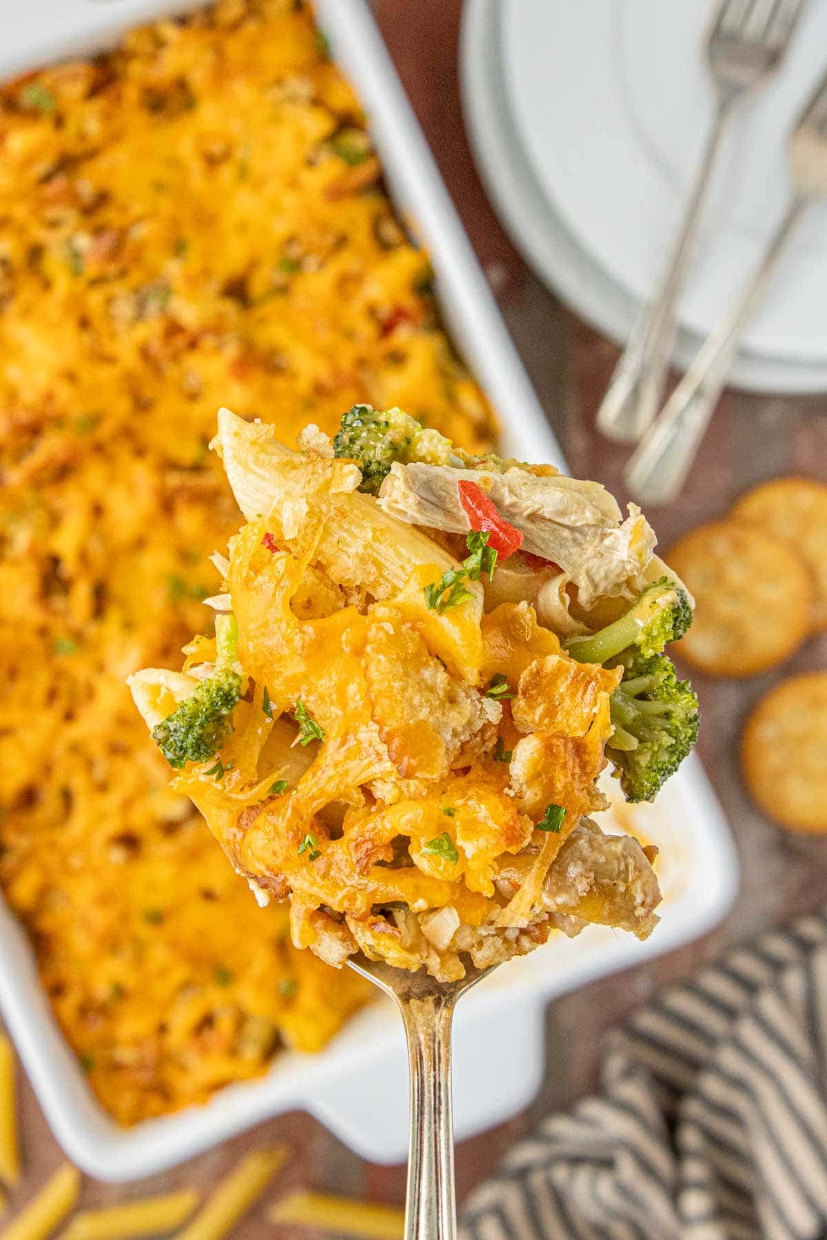 Cheesy pimento chicken casserole bite with broccoli and pasta lifted from baking dish.