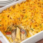 pimento cheese chicken casserole with creamy pasta, broccoli, and melted cheddar topped with buttery crumbs in baking dish with spoonful missing because someone couldn’t wait