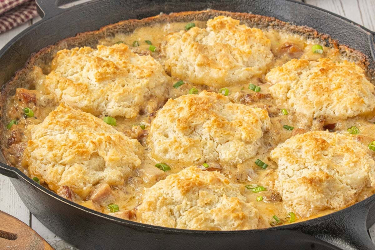Biscuits and sausage gravy pot pie topped with golden homemade biscuits in a cast iron skillet