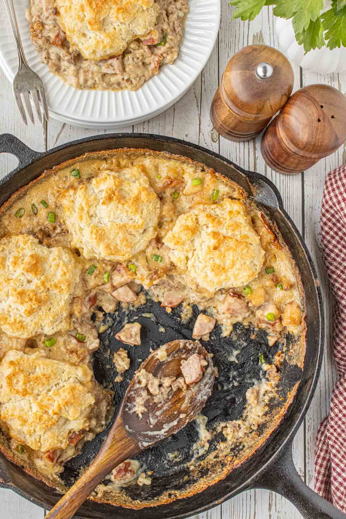 Biscuits and gravy pot pie served in a cast iron skillet with smoked sausage, creamy gravy, and homemade buttermilk biscuits