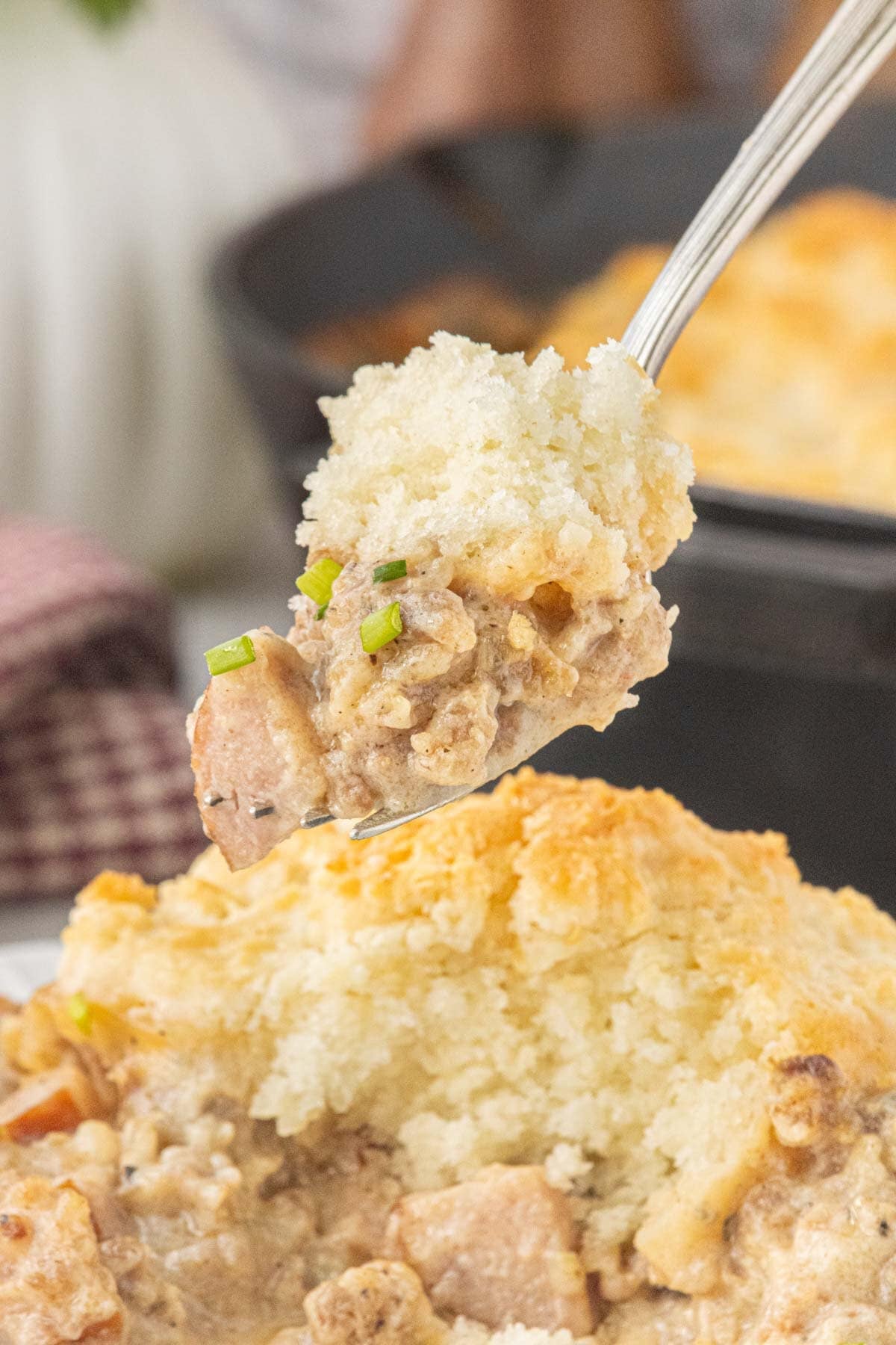 Forkful of biscuits and gravy pot pie with smoked sausage and flaky homemade biscuit