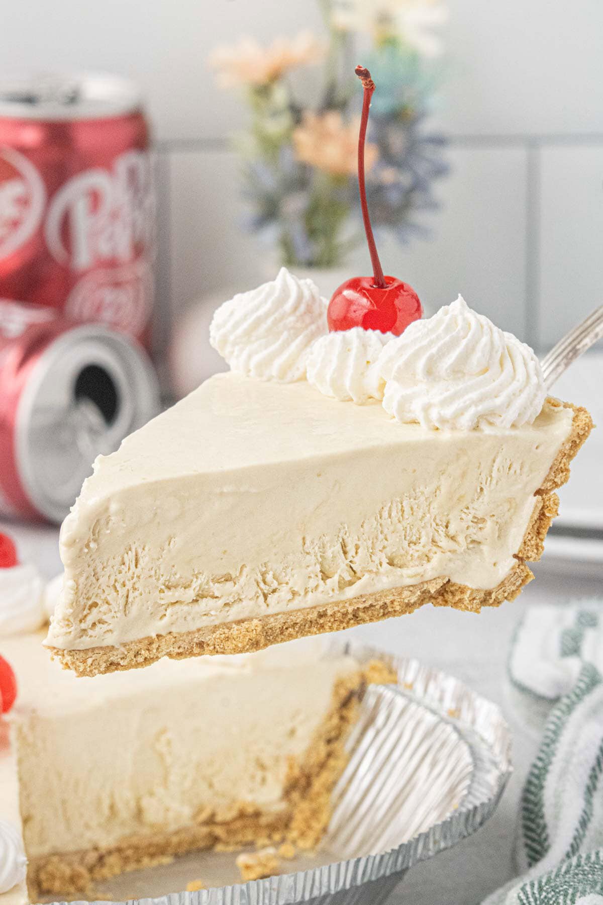 Slice of creamy Dr Pepper icebox pie topped with whipped cream and a maraschino cherry on a dessert plate.