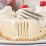 Fork cutting into a creamy slice of Dr Pepper icebox pie topped with whipped cream and cherries.