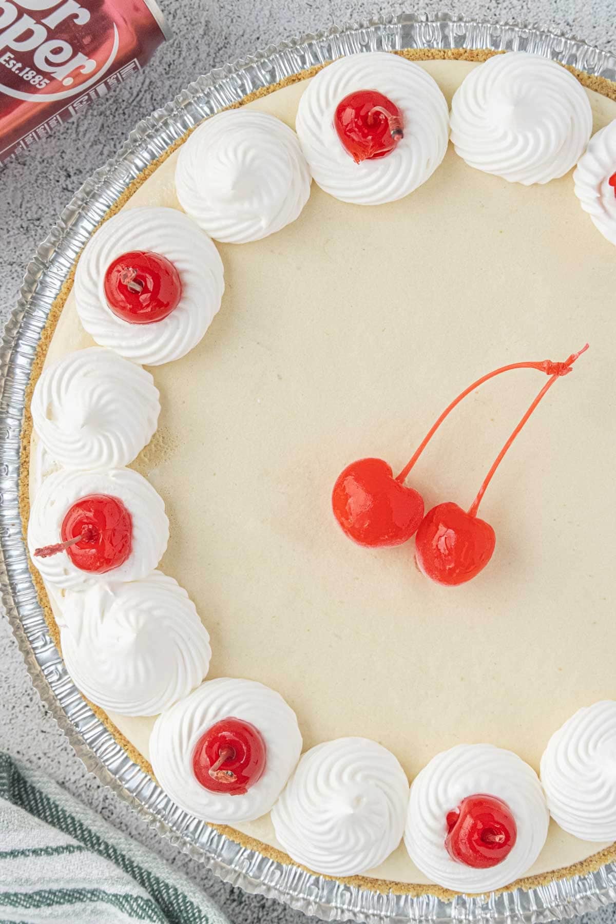 Overhead view of Dr Pepper icebox pie decorated with whipped cream swirls and maraschino cherries.