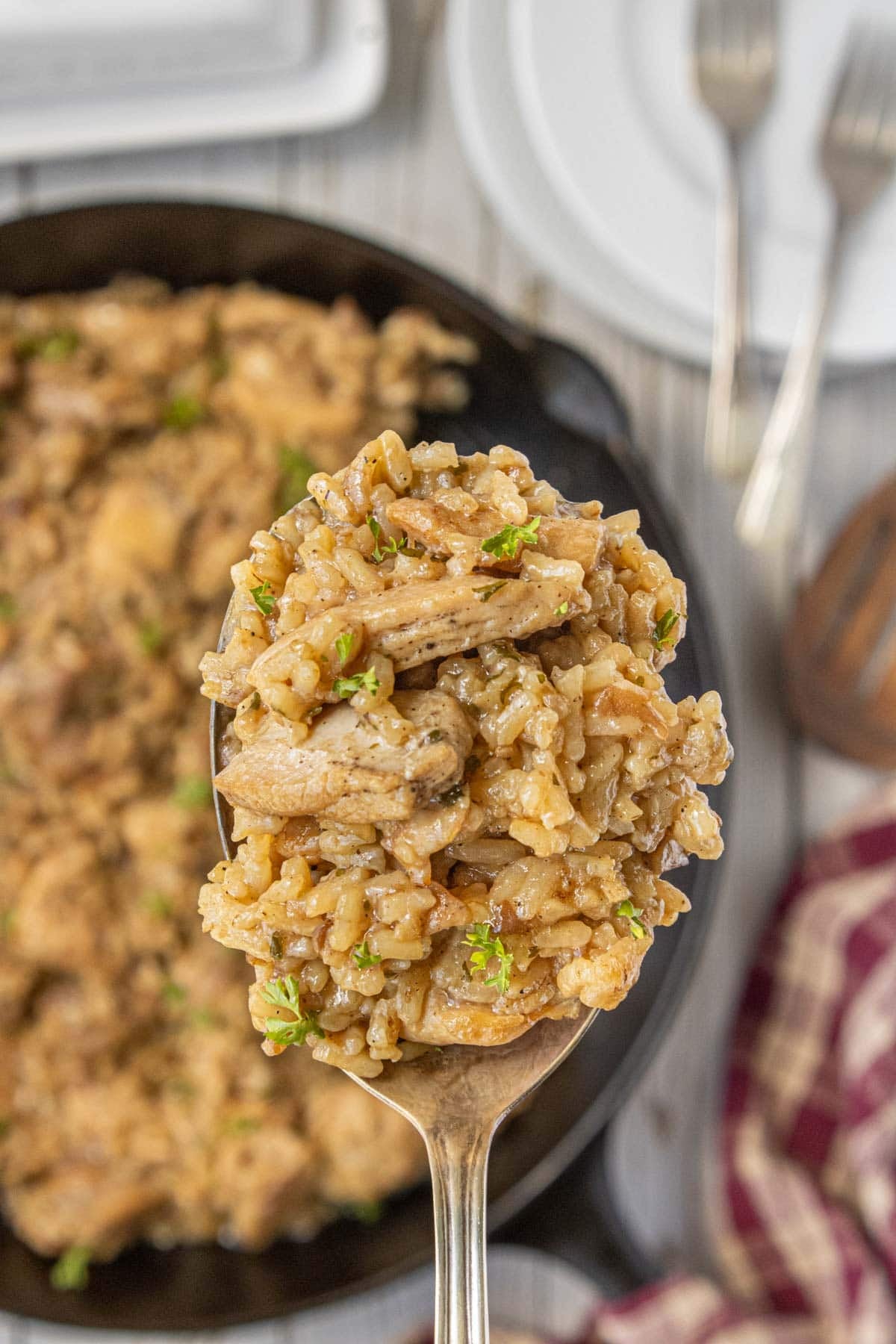 Spoonful of stick of butter chicken and rice casserole with juicy chicken, rice, and caramelized onions.