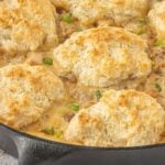 Cast iron biscuits and gravy pot pie topped with golden homemade biscuits and filled with creamy sausage gravy, smoked sausage, and onions.