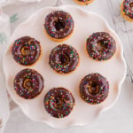 Overhead view of homemade baked pancake mix donuts with chocolate glaze arranged on a serving platter.