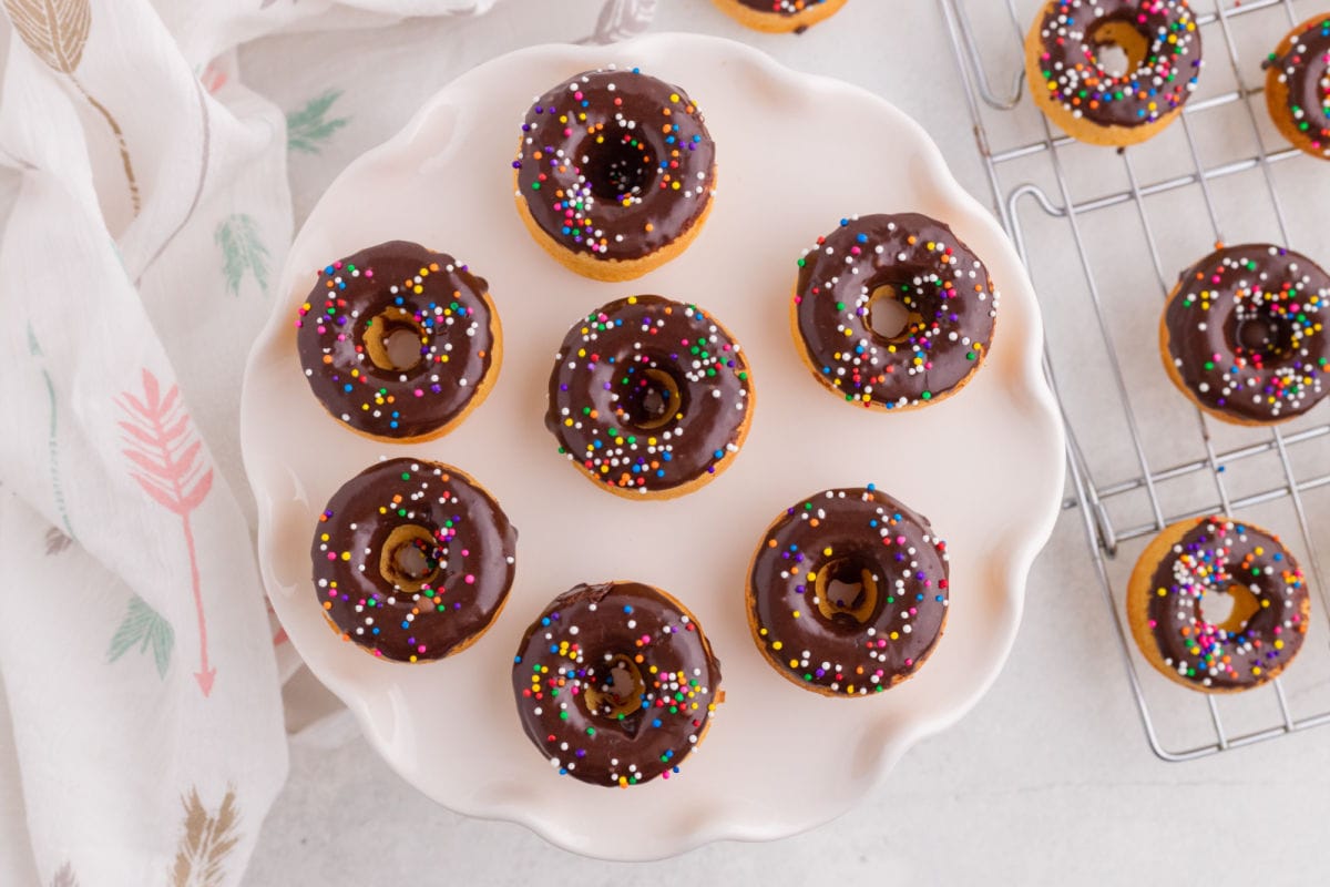 Overhead view of homemade baked pancake mix donuts with chocolate glaze arranged on a serving platter.
