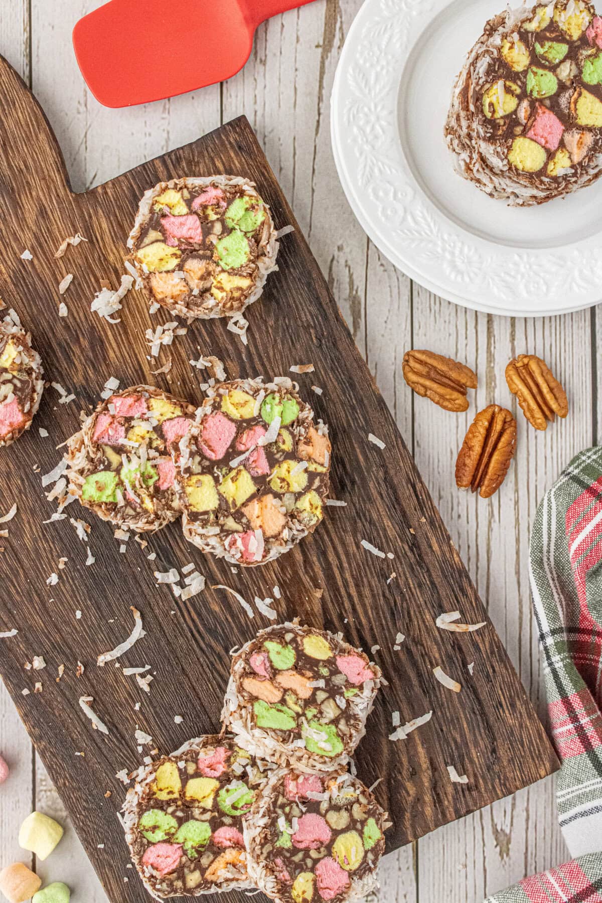 Sliced church window cookies arranged on a wooden cutting board with coconut flakes scattered around.