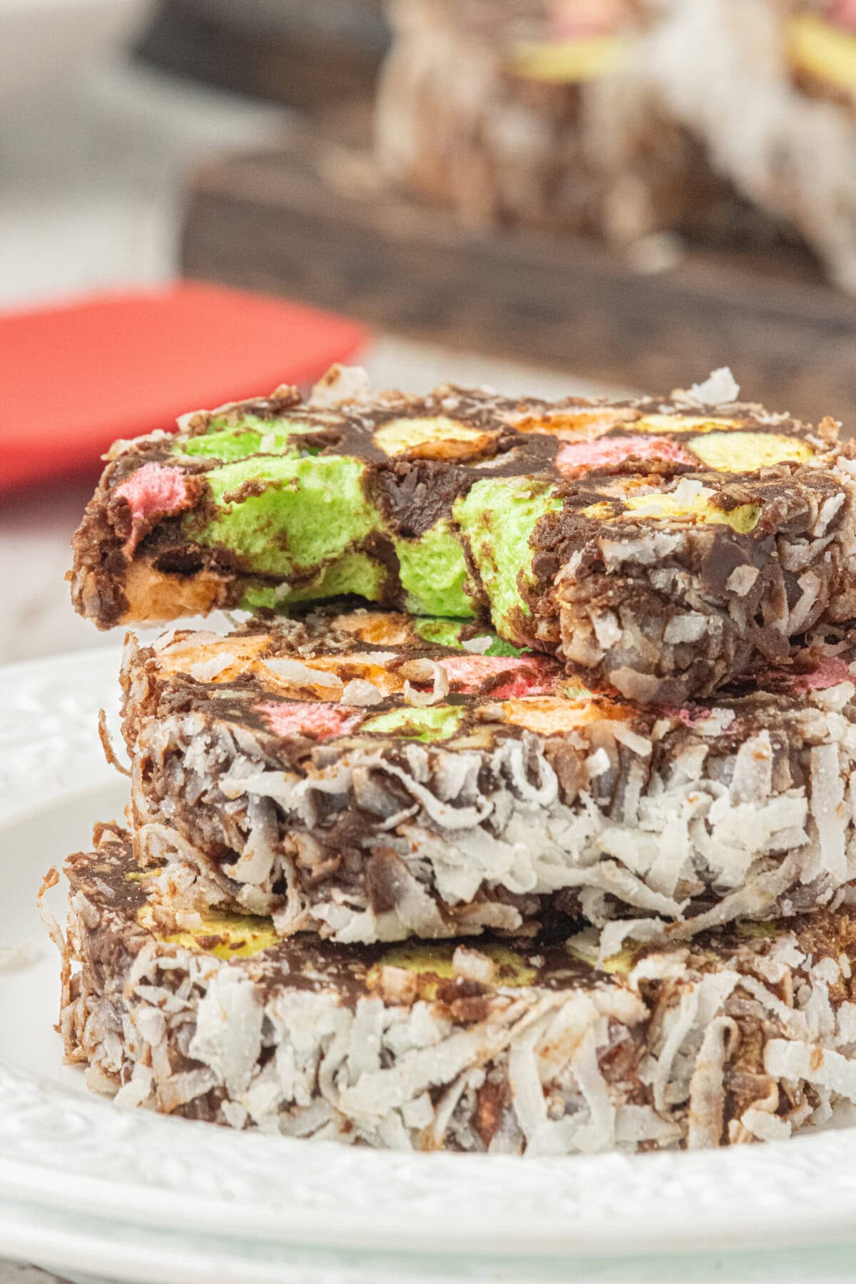 Side view of sliced church window cookies coated in coconut, showing colorful marshmallows inside rich chocolate.