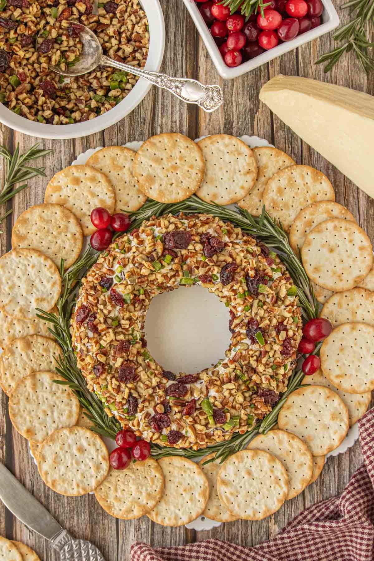 Festive cranberry cheese ball wreath appetizer served with crackers on a holiday platter.