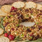 Homemade cranberry cheese ball wreath coated with pecans and dried cranberries for a Christmas appetizer.
