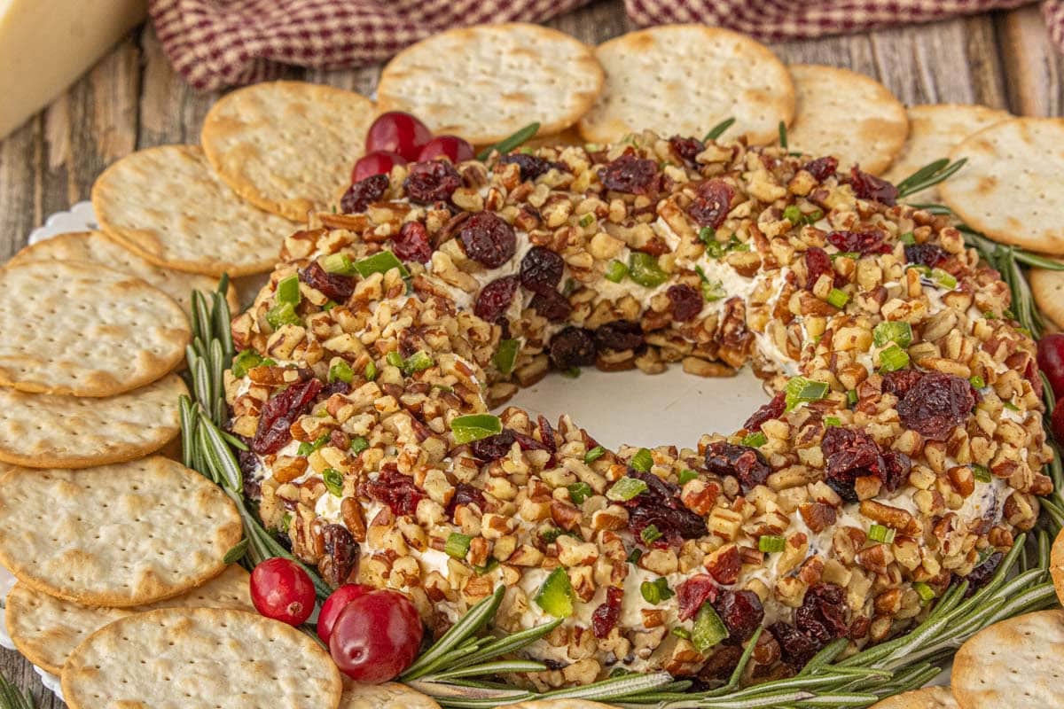 Homemade cranberry cheese ball wreath coated with pecans and dried cranberries for a Christmas appetizer.