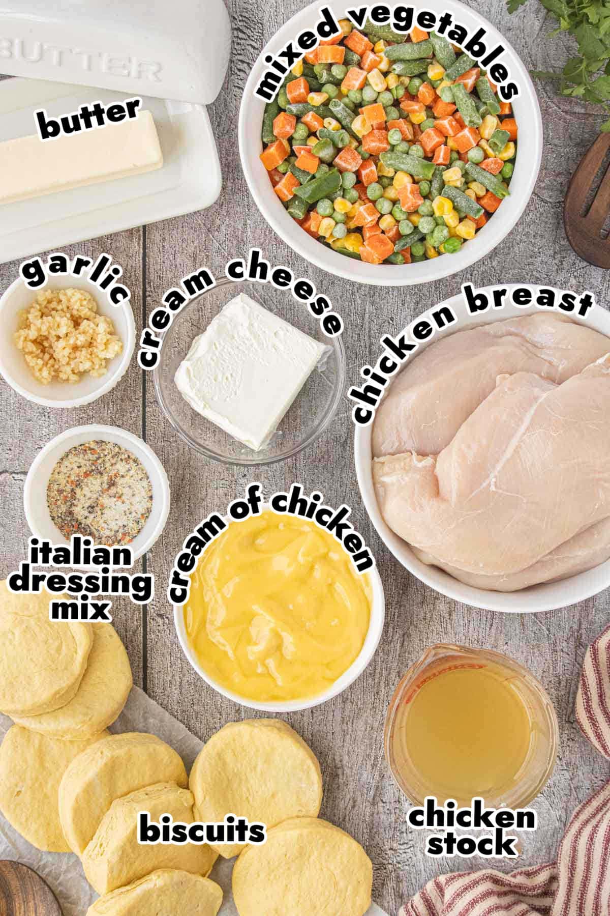 Ingredients for Crockpot Angel Chicken Pot Pie including chicken breasts, cream cheese, cream of chicken soup, Italian dressing mix, mixed vegetables, biscuits, butter, garlic, and chicken stock.