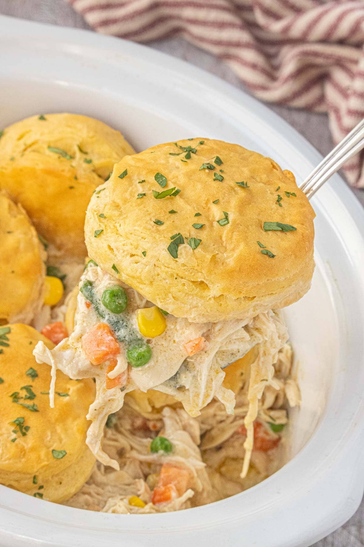 Spoonful of Crockpot Angel Chicken Pot Pie with creamy shredded chicken, vegetables, and a buttery biscuit on top.