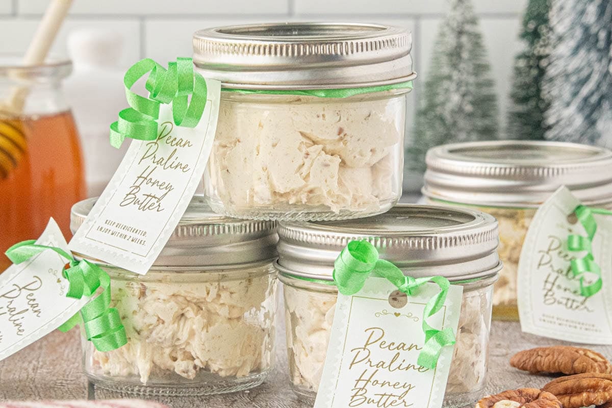 Homemade pecan praline honey butter packaged in small glass jars with gift tags and ribbons for easy Christmas food gifts.