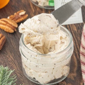 Jar of homemade pecan praline honey butter topped with a creamy swirl and chopped pecans, ready to spread on biscuits, toast, or muffins.