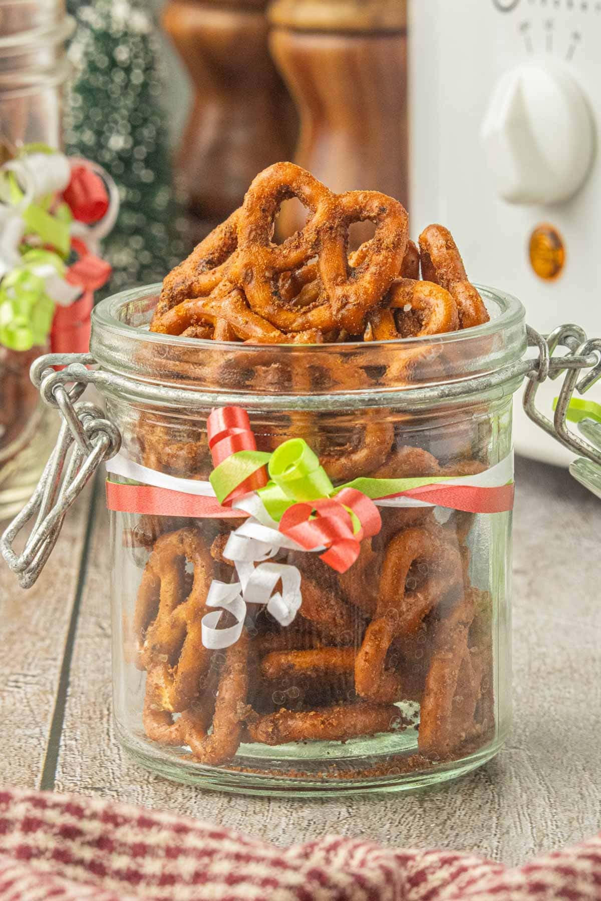 Slow cooker taco pretzels packaged in a glass clamp-top jar with a festive ribbon for homemade holiday gifts.
