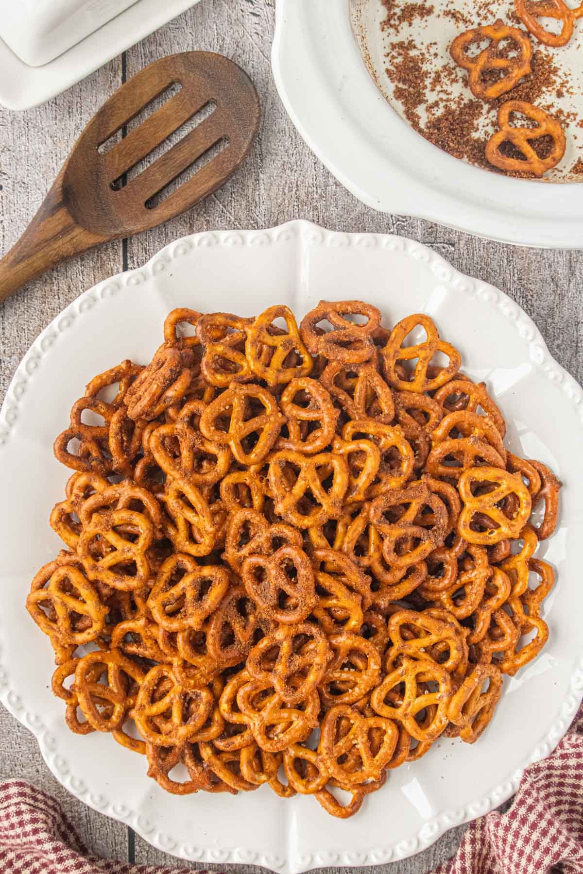 Slow cooker taco pretzels piled on a white serving platter with seasoned pretzels in the slow cooker behind them.