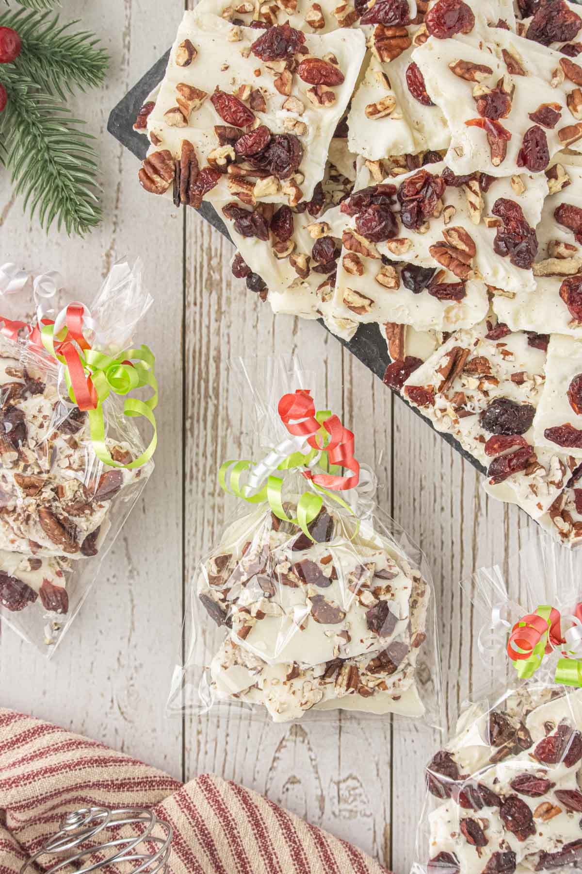 Homemade white chocolate cranberry bark packaged in clear gift bags with colorful ribbon for holiday gifts.