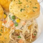 An image of a spoon lifting some of the biscuit topped angel chicken pot pie out of the slow cooker with text for Pinterest.