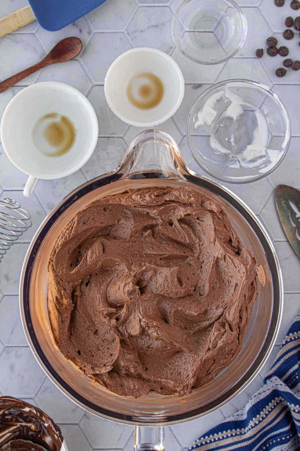 Bowl of homemade chocolate fudge frosting with a rich, silky texture ready to spread on cakes and cupcakes.