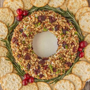 Cranberry cheese ball wreath surrounded by crackers, rosemary sprigs, and fresh cranberries.