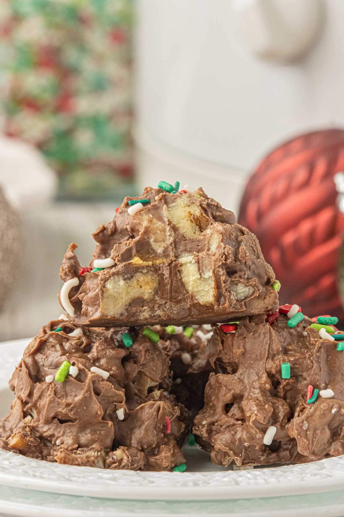Stack of homemade crockpot candy with pecans, toffee bits, and chocolate topped with festive Christmas sprinkles.