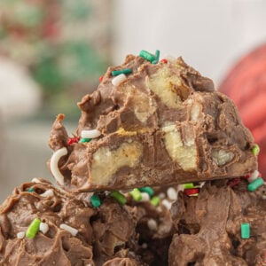 Close-up of homemade crockpot candy made with chocolate, pecans, and toffee bits topped with Christmas sprinkles.