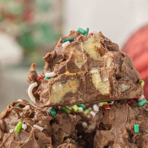 Close-up of homemade crockpot candy made with chocolate, pecans, and toffee bits topped with Christmas sprinkles.