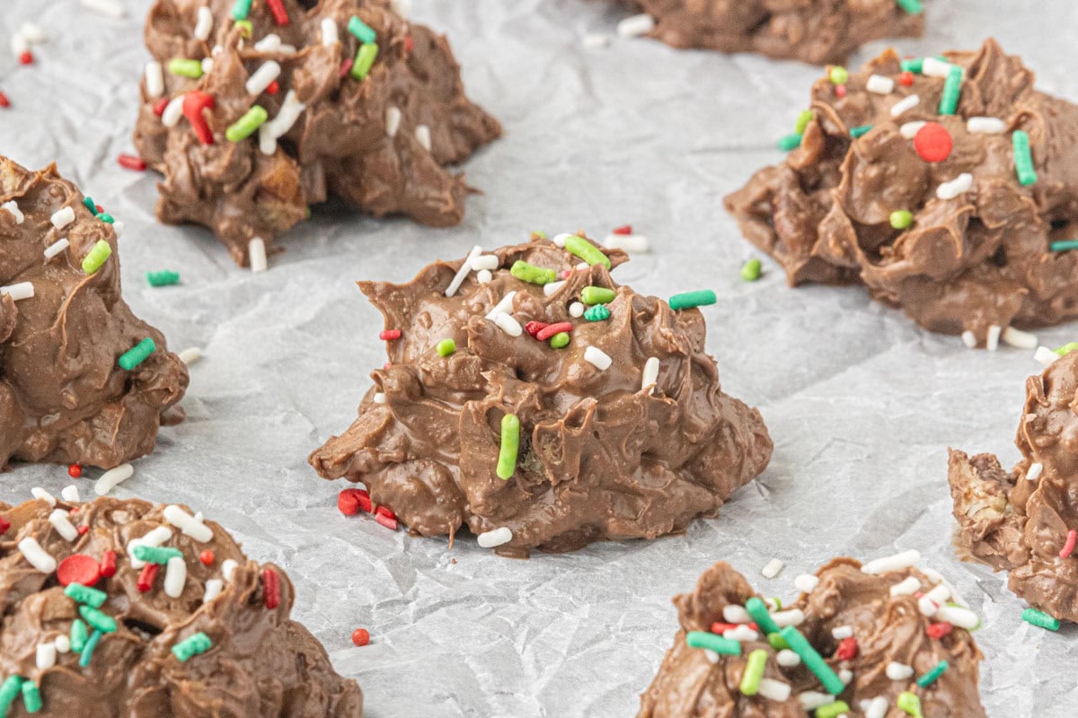 Pieces of homemade crockpot candy on parchment paper decorated with red, green, and white Christmas sprinkles.
