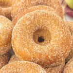 Fresh baked apple cider donuts coated in cinnamon sugar and stacked together.