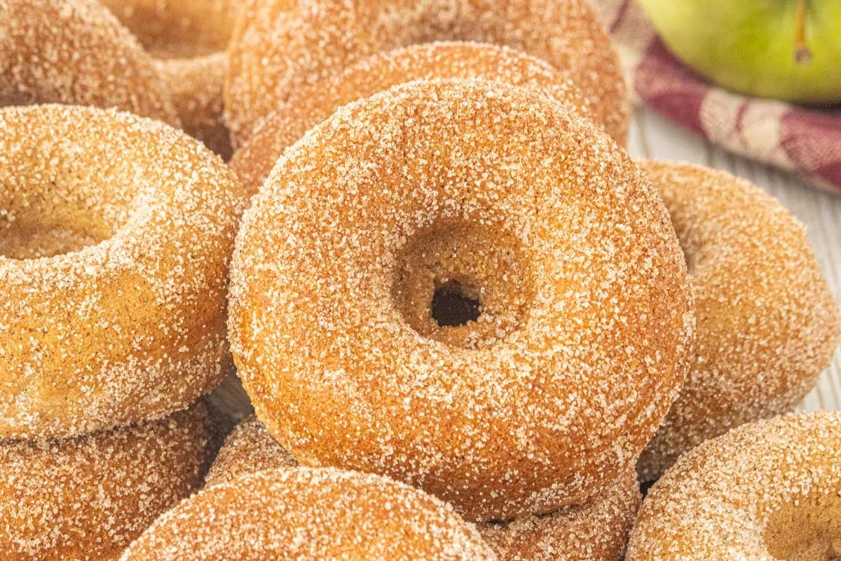 Fresh baked apple cider donuts coated in cinnamon sugar and stacked together.