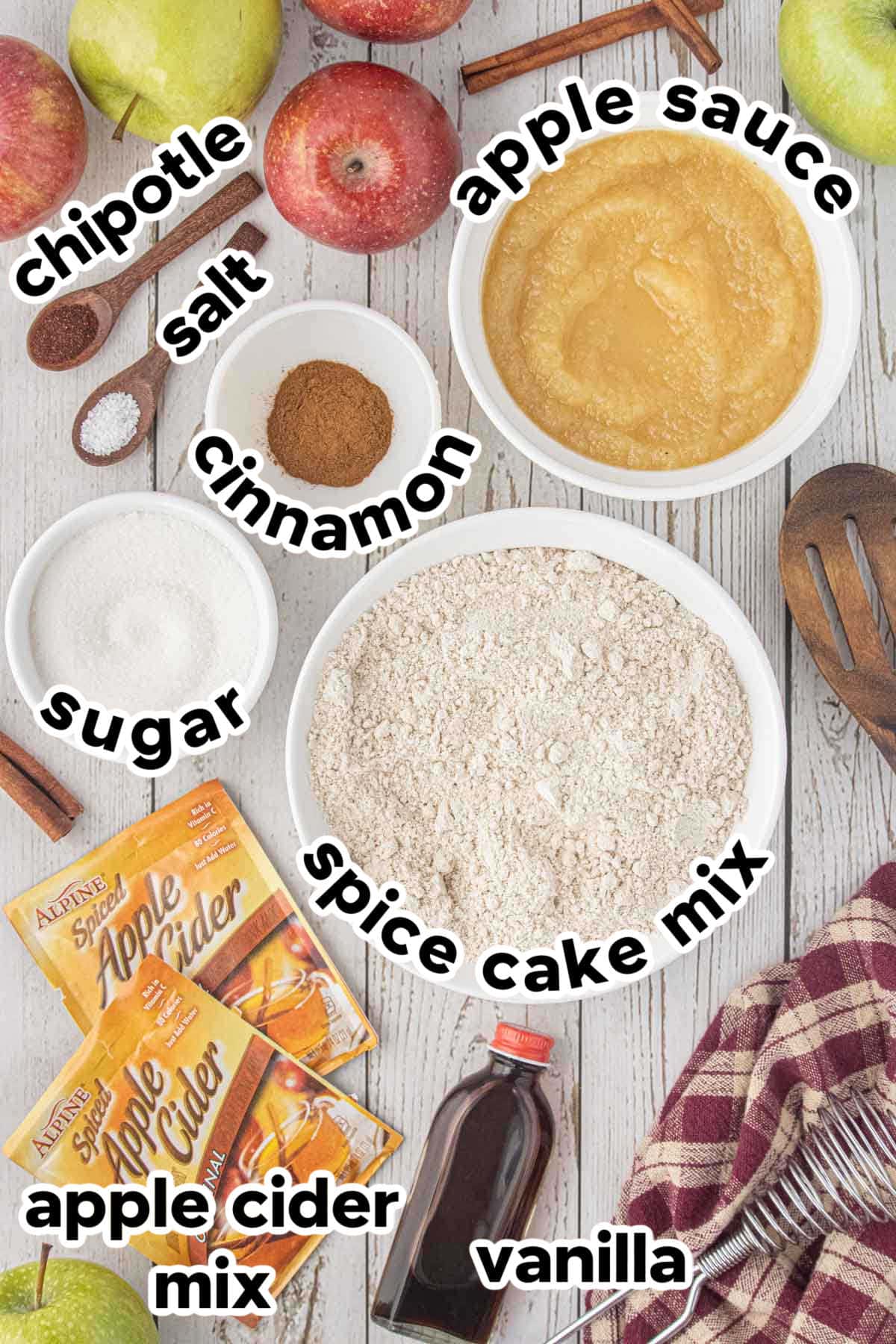 Ingredients for baked apple cider donuts including spice cake mix, applesauce, apple cider drink mix, cinnamon, sugar, vanilla, chipotle powder, and salt.