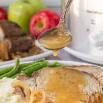 Slow cooker apple cider pork loin roast being drizzled with apple cider sauce.