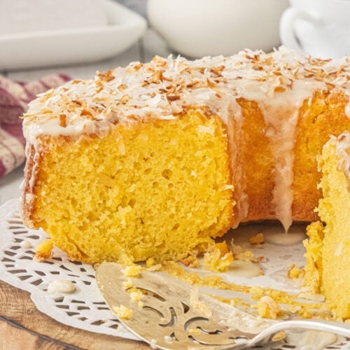 Louisiana crunch cake with vanilla glaze and toasted coconut on top sliced open to see the velvety, moist crumb.