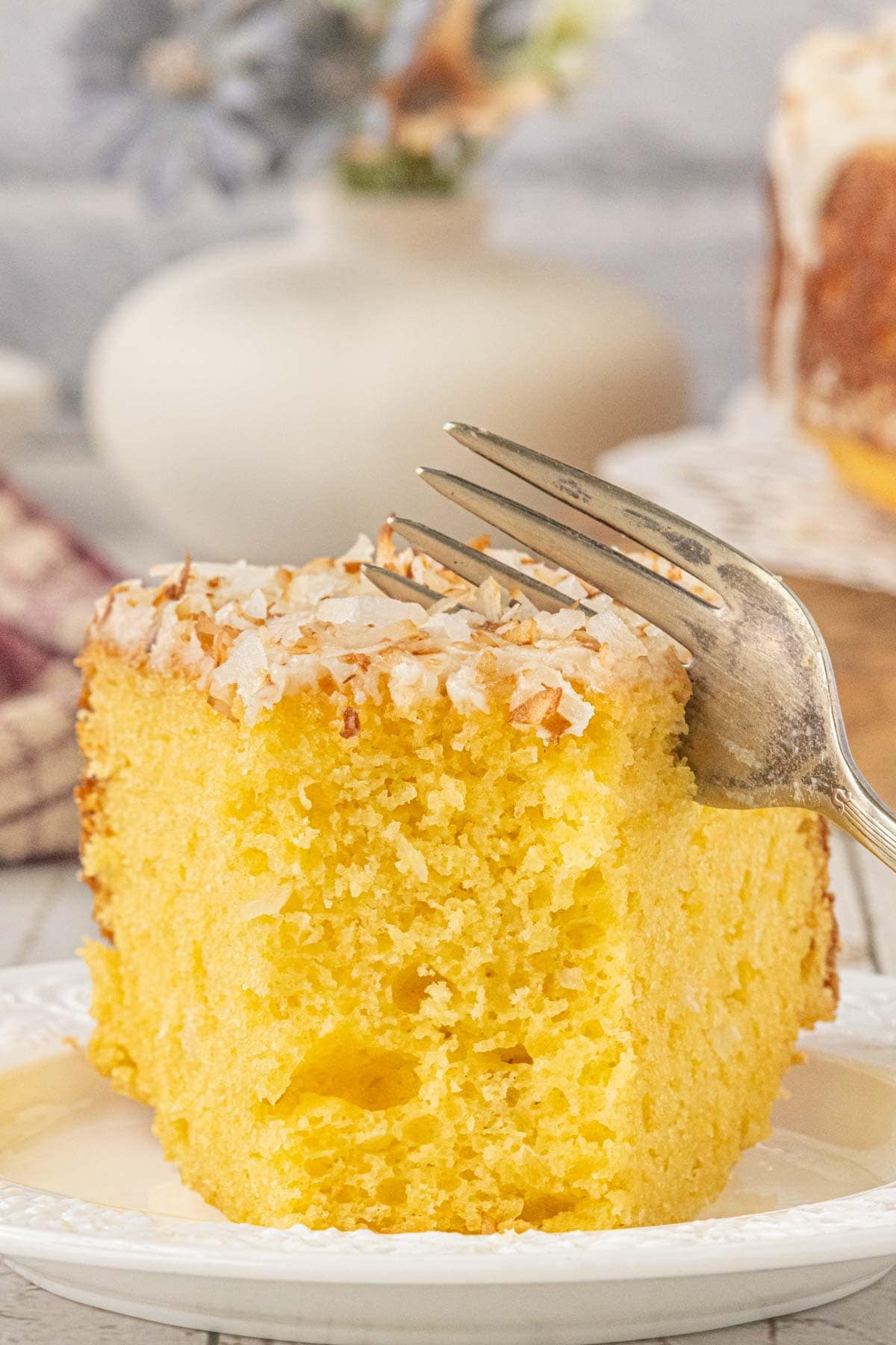 Slice of Louisiana crunch cake topped with vanilla glaze and toasted coconut
