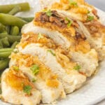 Ritz chicken sliced on a white plate with green beans and crispy golden cracker topping