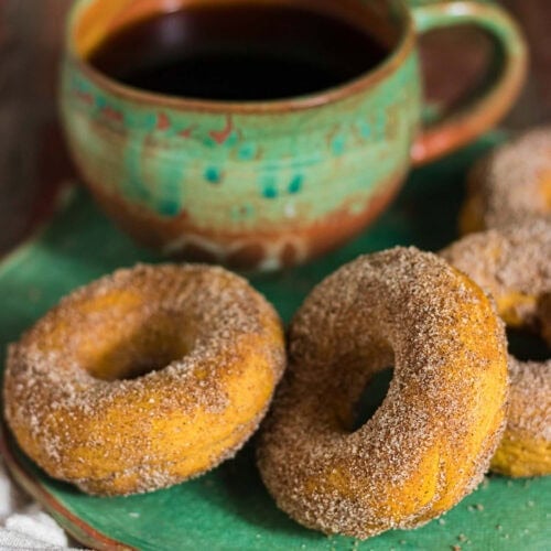 Baked pumpkin donuts coated in cinnamon sugar served with a cup of coffee