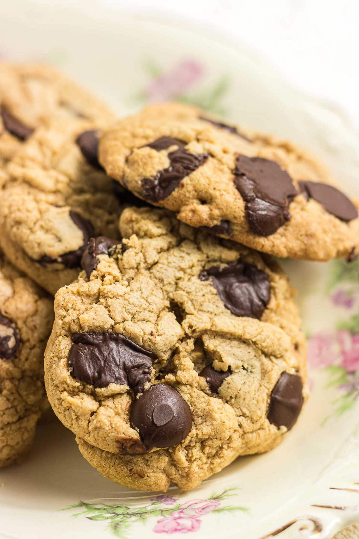 Chewy gluten-free brown butter chocolate chip cookies loaded with melted chocolate chips on a vintage floral plate