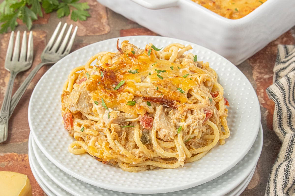Serving of creamy BBQ chicken spaghetti casserole with shredded chicken, Rotel tomatoes, and smoked Gouda on a white plate