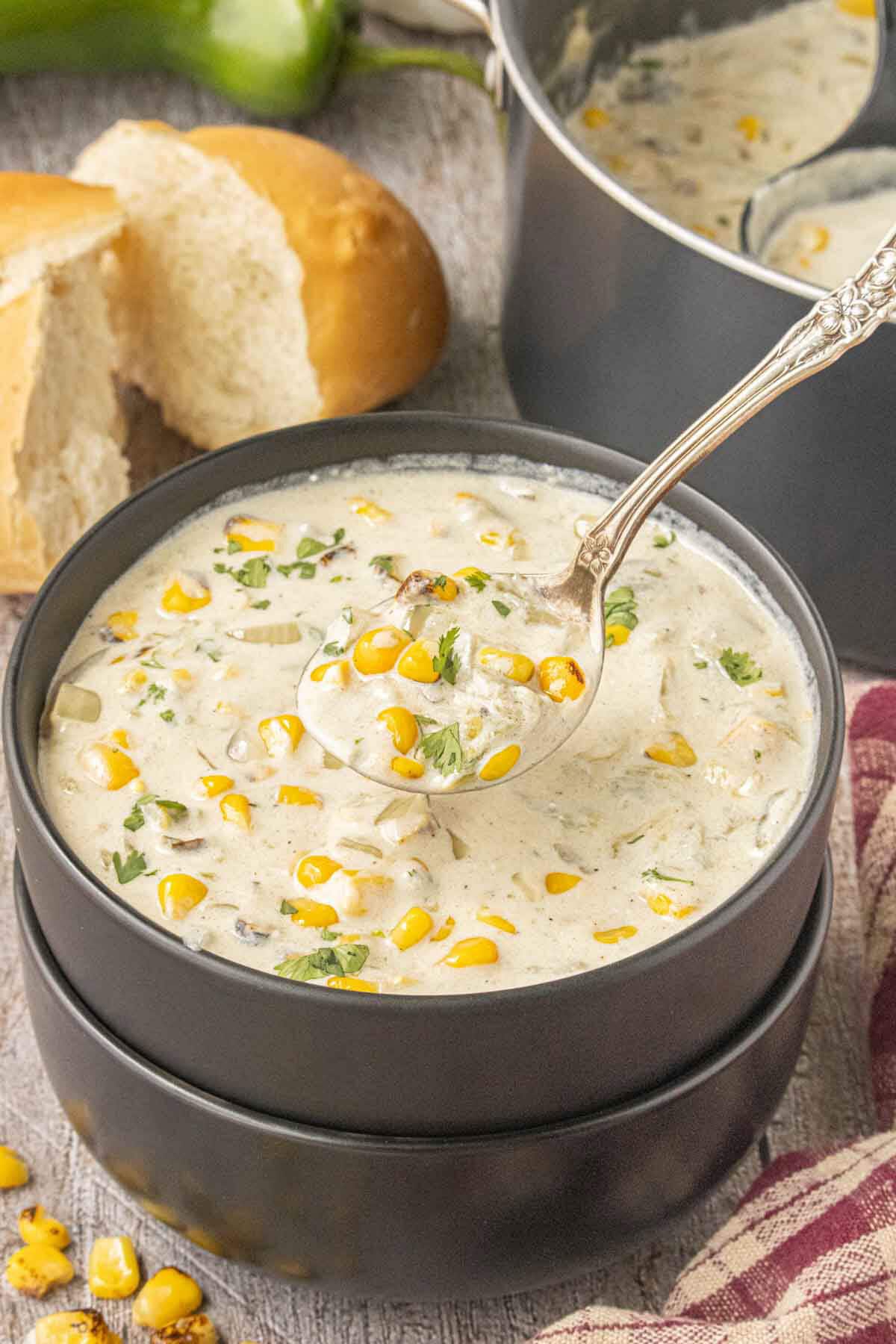 Hatch chile corn chowder in a black bowl with roasted corn, green chiles, and crusty bread