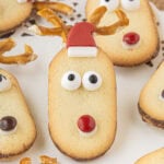 No-bake Milano reindeer cookies decorated with pretzel antlers, candy eyes, and M&M noses