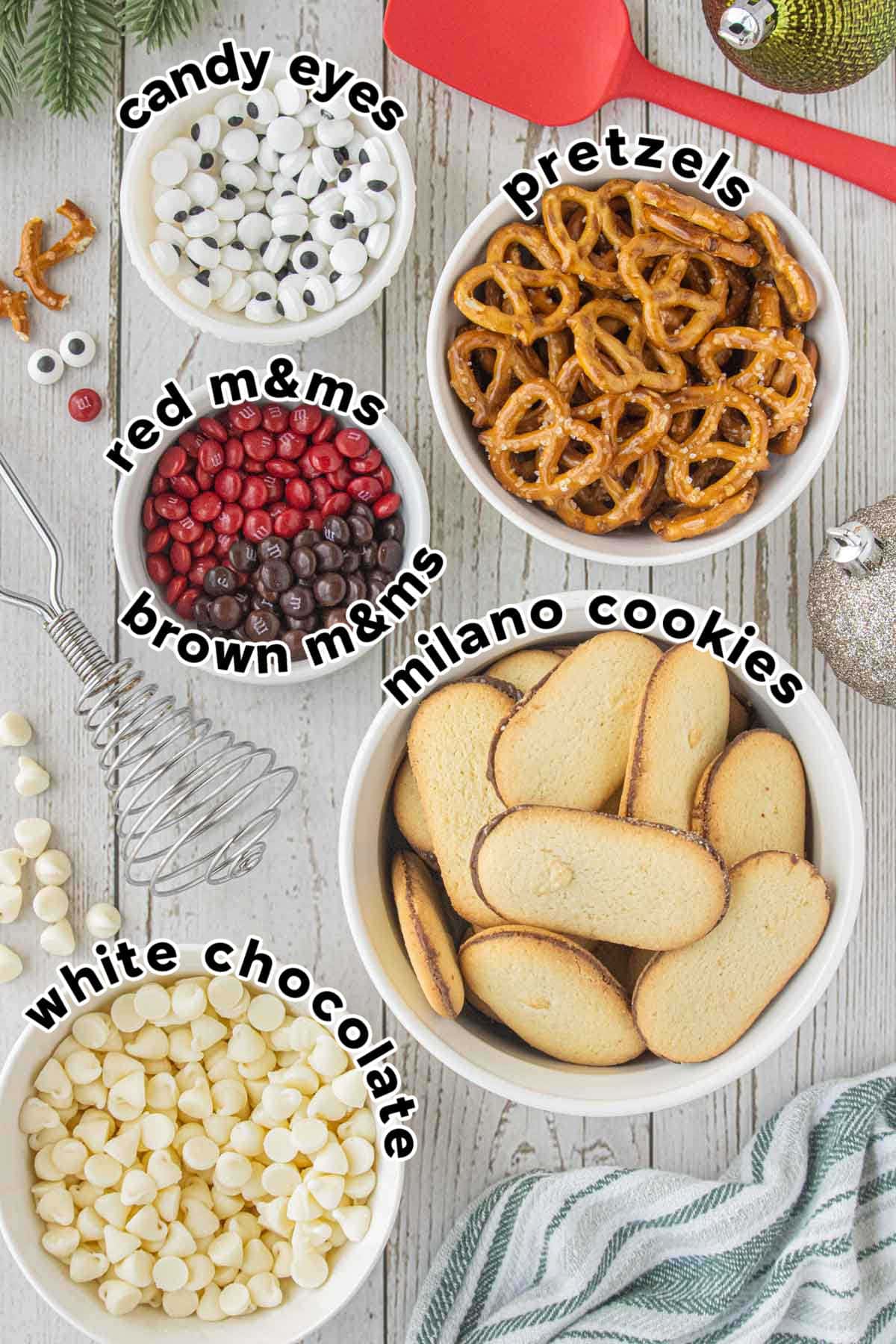 Ingredients for reindeer cookies with Milano cookies, pretzels, candy eyes, M&Ms, and white chocolate