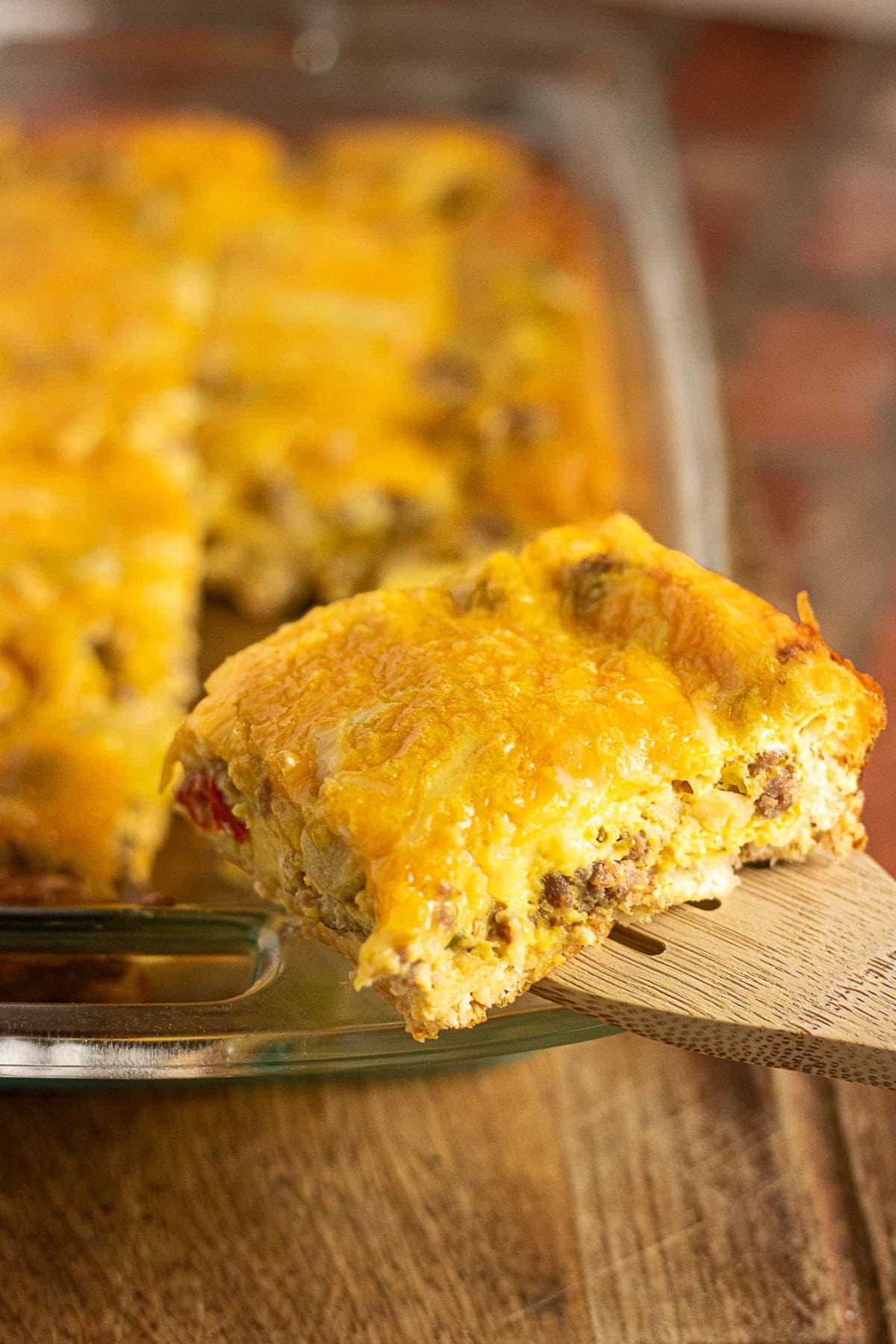 Cheesy crescent roll breakfast casserole with sausage, eggs, peppers, and onions being served