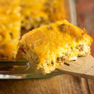 A closeup of a serving of easy crescent roll breakfast casserole with sausage and peppers being removed from the casserole dish.