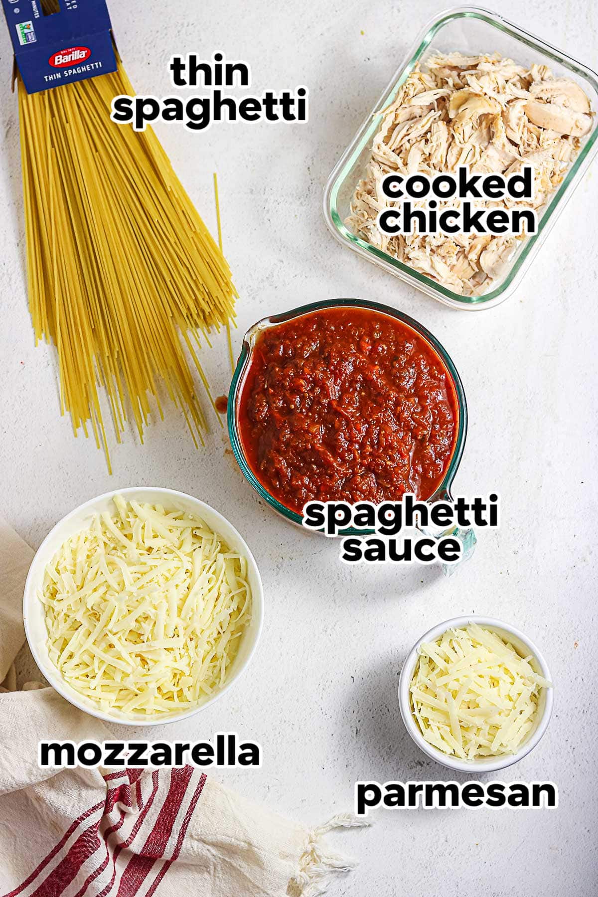 Ingredients for chicken spaghetti with red sauce including thin spaghetti, chicken, spaghetti sauce, mozzarella, and Parmesan