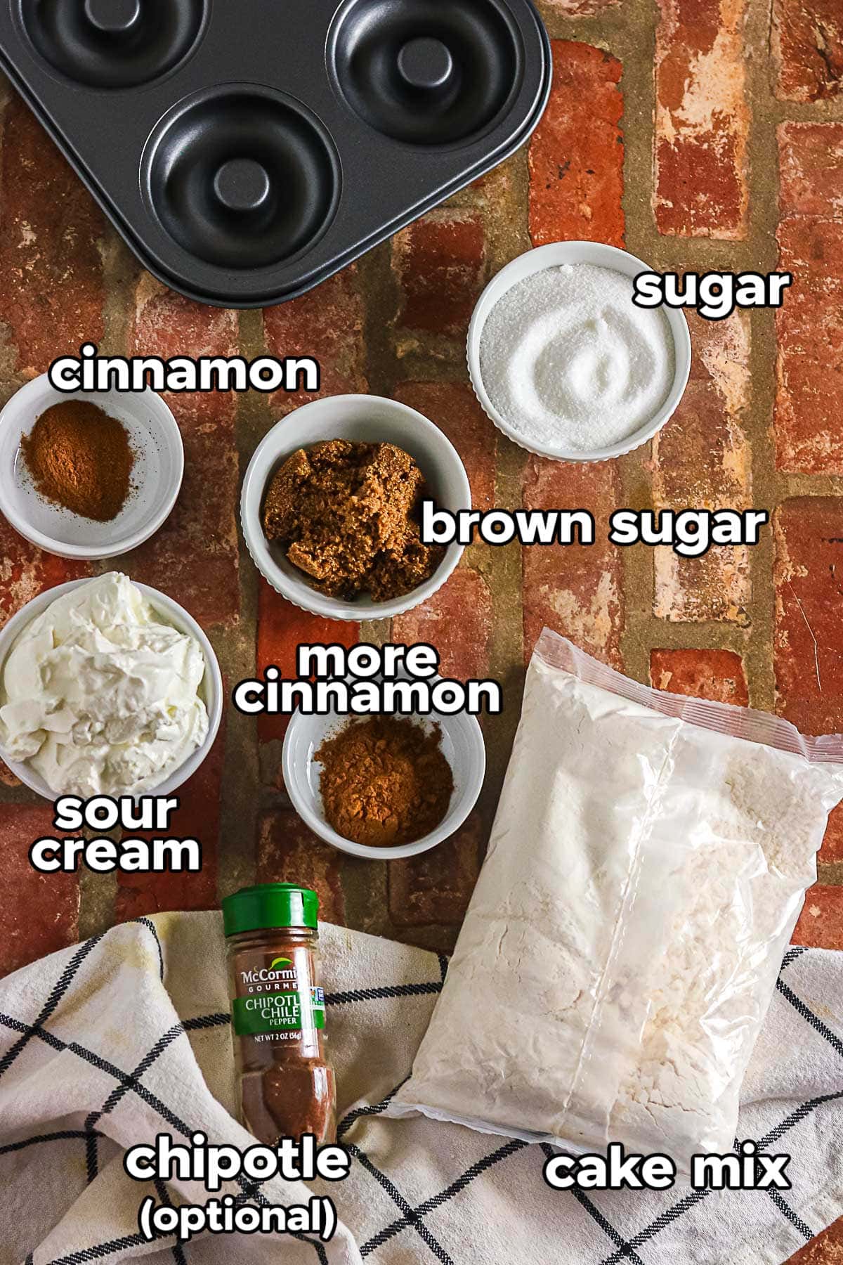 Ingredients for cinnamon baked donuts including cake mix, sour cream, brown sugar, cinnamon, sugar, and optional chipotle